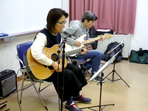 50代女性の生徒さんと講師のギター演奏の様子を横側から