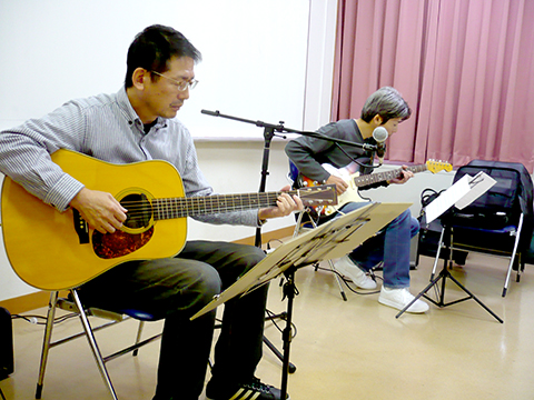 50代男性の生徒さんと講師のギター演奏の様子