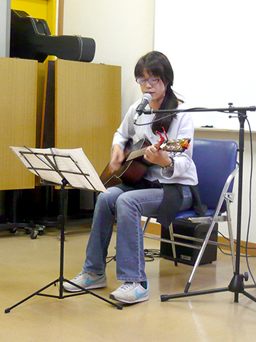 一人でギターを弾き語りする40代女性の生徒さんの写真