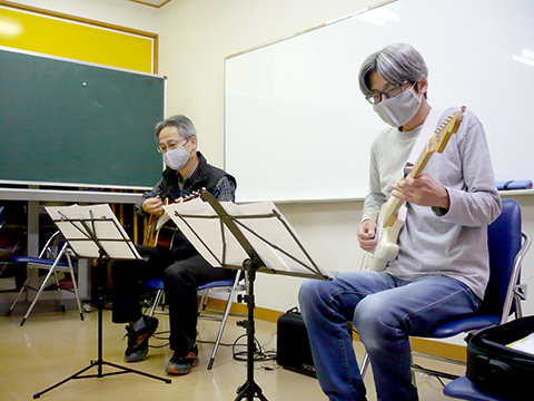 60代男性の生徒さんと講師のギター演奏の別角度の写真