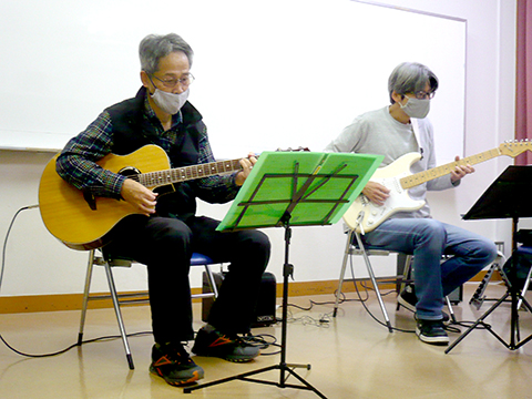 60代男性の生徒さんと講師のギター演奏の写真