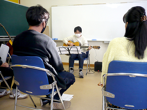 ギターを弾く生徒さん（40代男性）と演奏を聴く生徒さんの様子