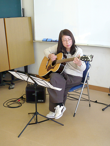 アコースティックギターを弾く生徒さん（50代女性）の様子