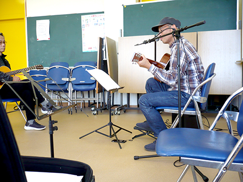 アコースティックギターを弾き語りする生徒さん（50代男性）の横からの様子