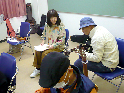 休憩時間にギターを弾く男性とそれを見る女性の様子