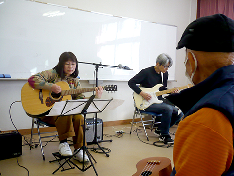 アコースティックギターを弾く50代女性と講師の演奏の様子