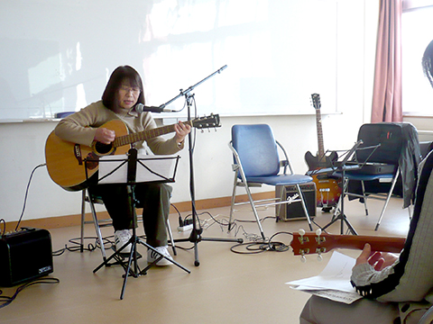 アコースティックギターを弾き語りする生徒さん(50代女性)の様子