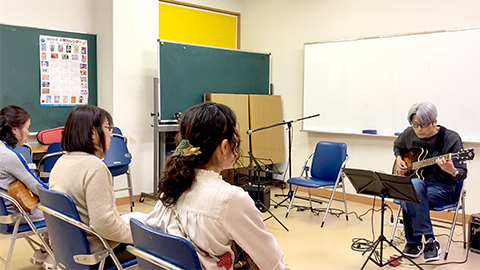 ギター講師のギター演奏とそれを聴く生徒さんたちの様子